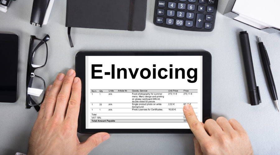 84537680 - directly above shot of businessman's hands going through e-invoicing on digital tablet in office